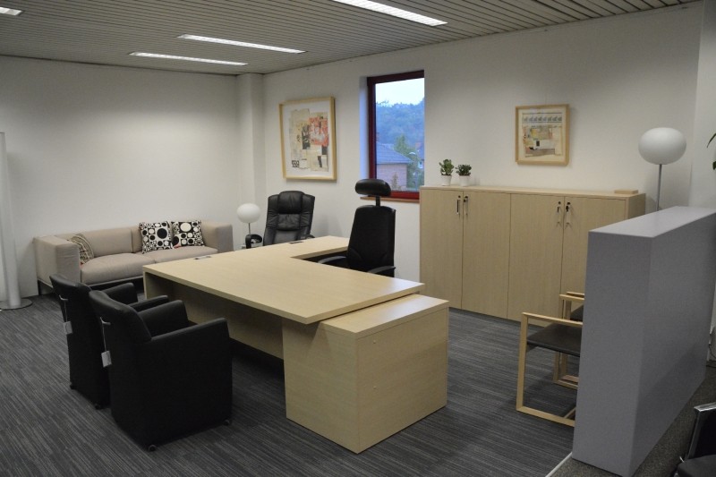 Bureau de direction Sinetica Ekis en chêne clair, avec 2 fauteuils visiteur Mobitec classico en cuir noir et un siège de travail Giroflex 64 en cuir noir avec têtière.